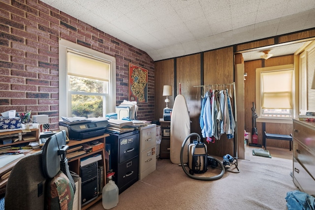 home office featuring light colored carpet, brick wall, and wood walls