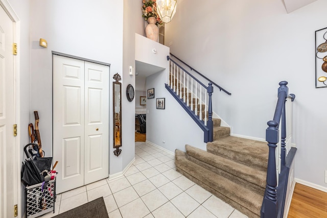 stairway featuring a high ceiling, tile patterned flooring, and baseboards