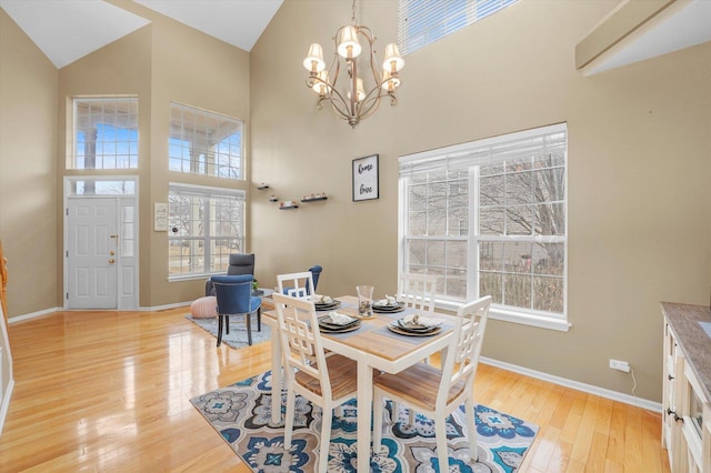 dining room with a notable chandelier, high vaulted ceiling, and light wood-type flooring