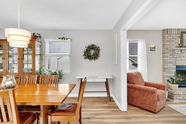 dining room with a brick fireplace and light hardwood / wood-style floors