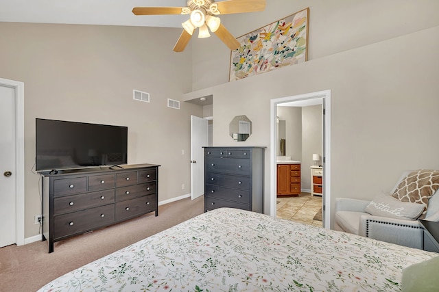 bedroom with ceiling fan, ensuite bath, light carpet, and a high ceiling