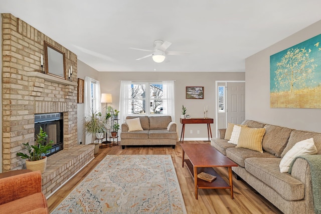 living room featuring a brick fireplace, light hardwood / wood-style flooring, and ceiling fan