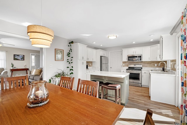 dining area with ceiling fan, sink, and light hardwood / wood-style flooring