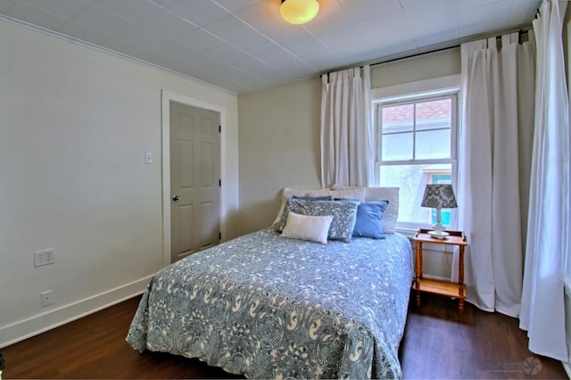 bedroom with baseboards and dark wood-type flooring