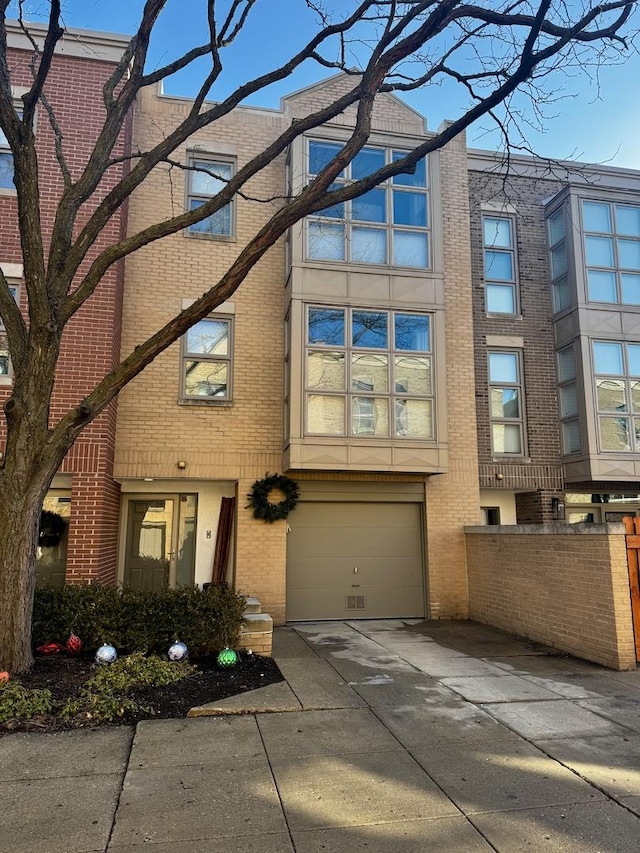 townhome / multi-family property with a garage, concrete driveway, and brick siding