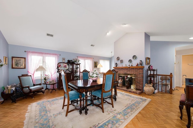 dining room with lofted ceiling, light parquet flooring, and a fireplace