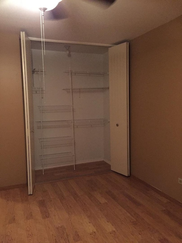 unfurnished bedroom with ceiling fan, hardwood / wood-style floors, and a closet