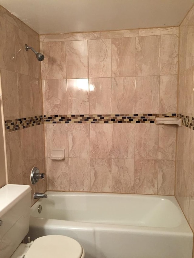 bathroom with tiled shower / bath combo and toilet