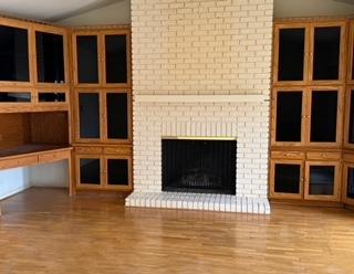 unfurnished living room with light wood-type flooring, vaulted ceiling, and a fireplace