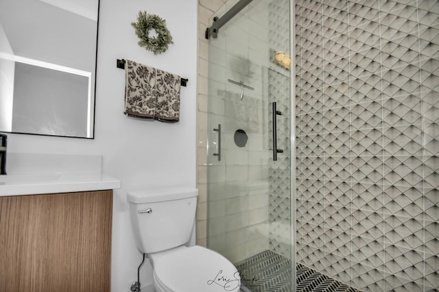 bathroom with toilet, vanity, and a shower with shower door