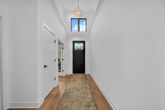 doorway to outside with light hardwood / wood-style floors, an inviting chandelier, and a high ceiling