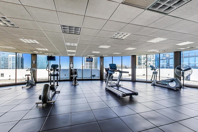 exercise room featuring a paneled ceiling, a wall of windows, and visible vents