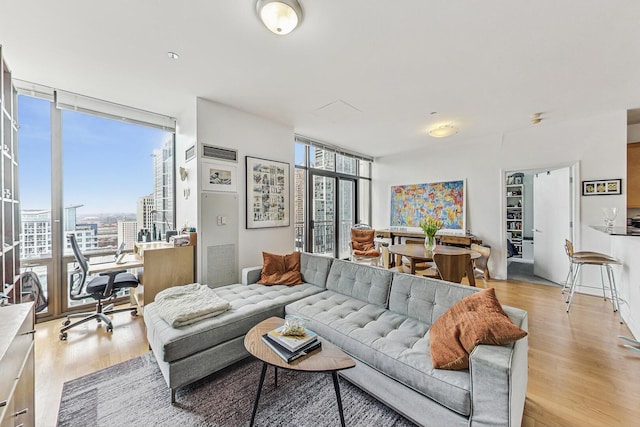 living room with light wood-type flooring, floor to ceiling windows, and visible vents