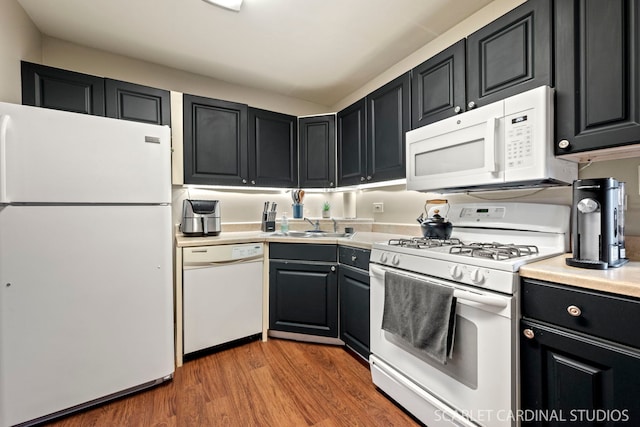 kitchen with hardwood / wood-style floors, white appliances, and sink