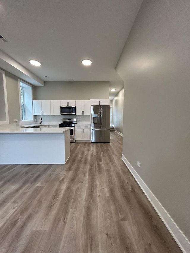 kitchen with white cabinetry, appliances with stainless steel finishes, and wood-type flooring