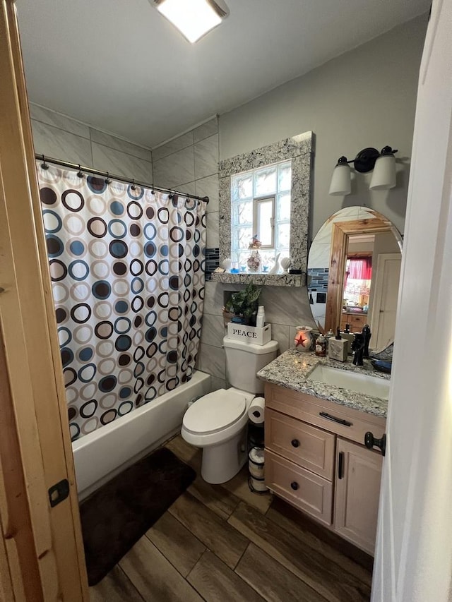 full bathroom featuring vanity, shower / tub combo, tile walls, and toilet