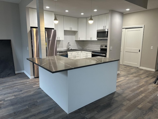 kitchen with white cabinetry, stainless steel appliances, dark wood-type flooring, and hanging light fixtures