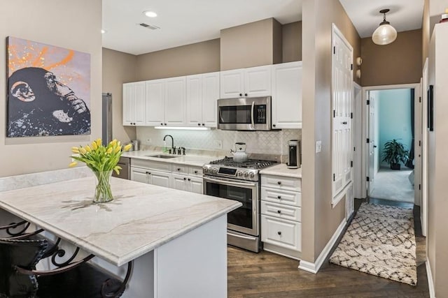 kitchen with dark wood-style flooring, stainless steel appliances, visible vents, decorative backsplash, and white cabinets