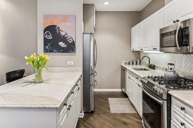 kitchen with a sink, white cabinets, appliances with stainless steel finishes, decorative backsplash, and dark wood finished floors