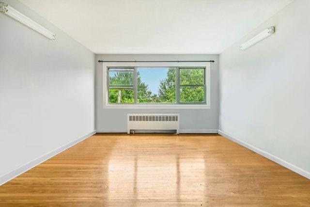 empty room featuring radiator heating unit and light hardwood / wood-style floors