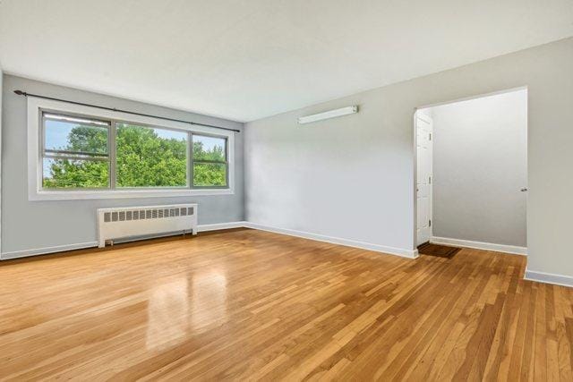 unfurnished room featuring radiator heating unit and light wood-type flooring