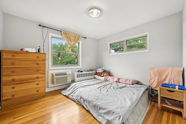 bedroom featuring hardwood / wood-style floors, radiator, and a wall mounted AC