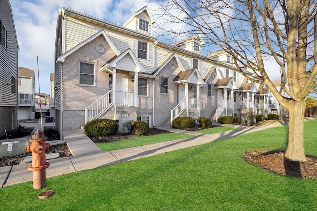 view of property featuring brick siding, a front lawn, and a residential view