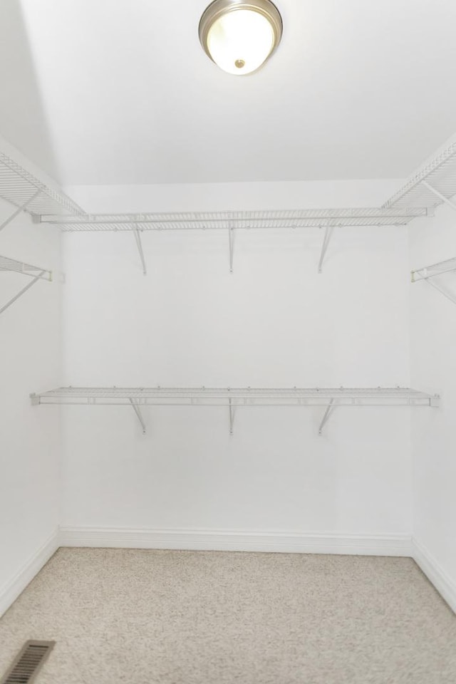 walk in closet with visible vents and light colored carpet