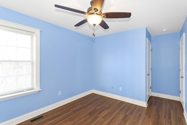 unfurnished room featuring baseboards, visible vents, dark wood finished floors, and a ceiling fan