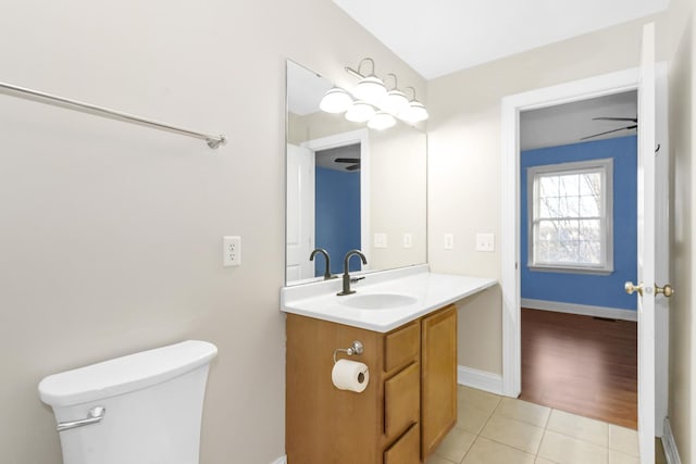 half bathroom with baseboards, a ceiling fan, toilet, tile patterned flooring, and vanity