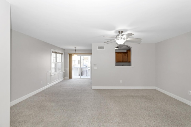 empty room with a ceiling fan, carpet flooring, visible vents, and baseboards