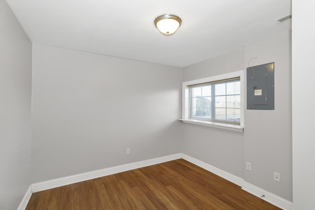 unfurnished room featuring visible vents, electric panel, baseboards, and dark wood-style flooring