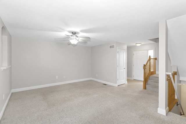 spare room with baseboards, stairway, visible vents, and light colored carpet