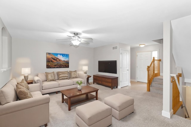 living room with light colored carpet, visible vents, stairway, and baseboards