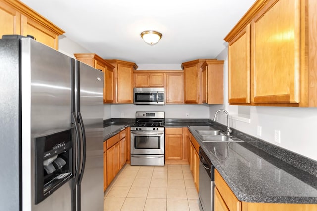 kitchen with light tile patterned floors, dark stone counters, brown cabinets, stainless steel appliances, and a sink