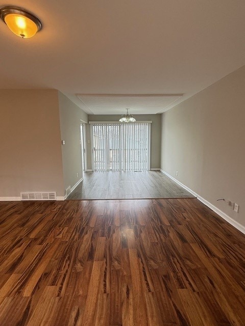 empty room featuring an inviting chandelier and hardwood / wood-style flooring