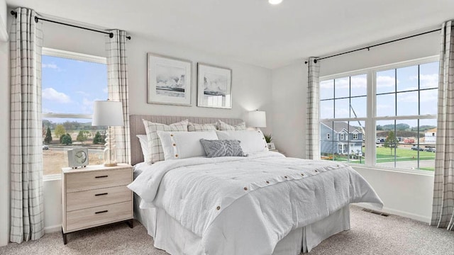 bedroom with light carpet, multiple windows, and visible vents