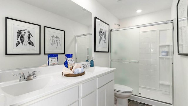 full bath featuring a shower with shower door, a sink, toilet, and double vanity