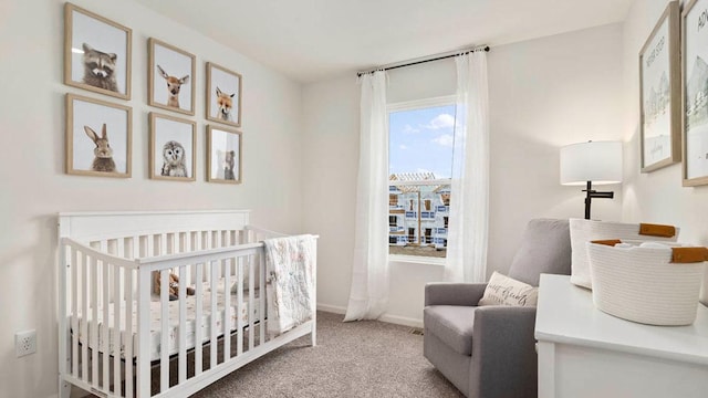 bedroom featuring a crib, baseboards, and light colored carpet