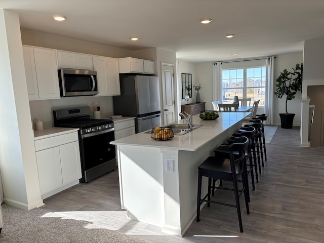 kitchen featuring appliances with stainless steel finishes, light countertops, an island with sink, and white cabinetry