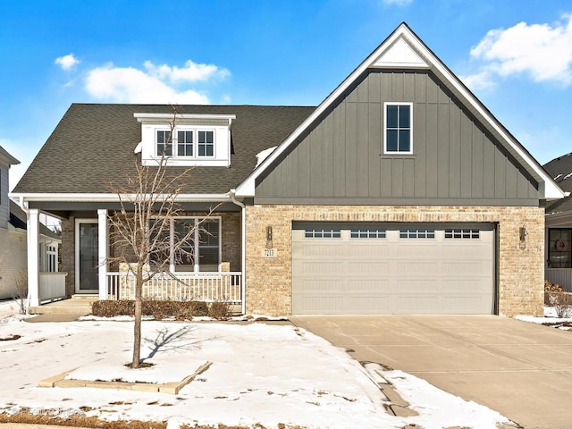 view of front of property featuring brick siding, a shingled roof, covered porch, a garage, and driveway