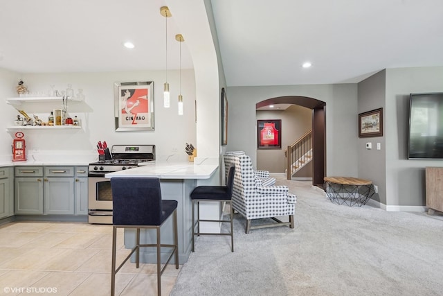 37580 N Fairfield Rd, Lake Villa, IL 60046 - kitchen with gas stove, arched walkways, a breakfast bar area, light countertops, and a peninsula