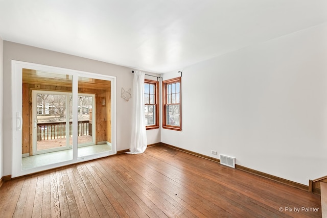 spare room with baseboards, visible vents, and wood finished floors