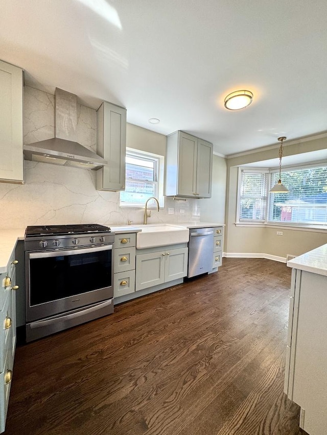 kitchen with sink, decorative light fixtures, wall chimney range hood, stainless steel appliances, and backsplash