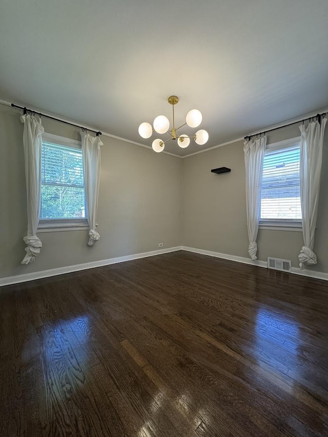 spare room with plenty of natural light, dark hardwood / wood-style floors, and an inviting chandelier