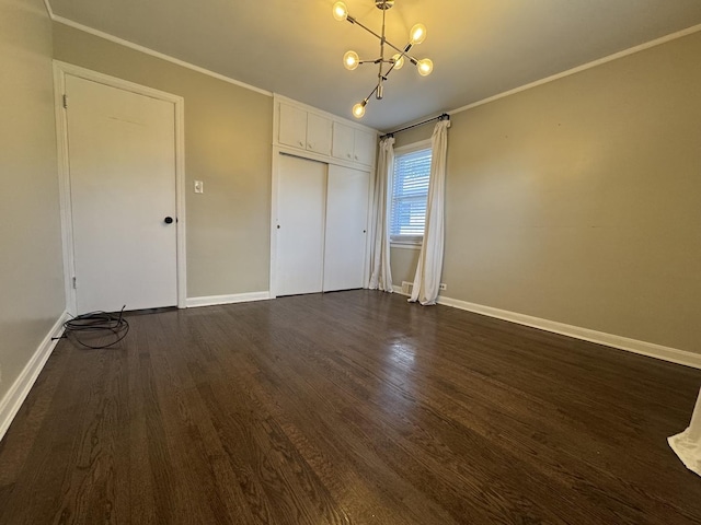 unfurnished bedroom with crown molding, a chandelier, dark hardwood / wood-style flooring, and a closet