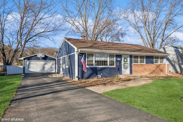 view of front of property featuring driveway, a chimney, a detached garage, a front lawn, and brick siding