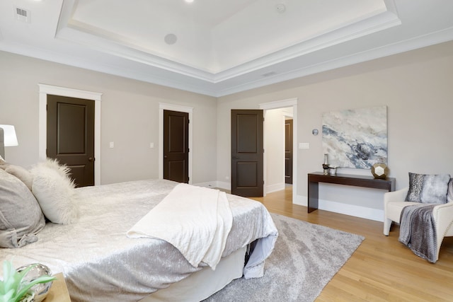 bedroom featuring hardwood / wood-style flooring, ornamental molding, and a tray ceiling