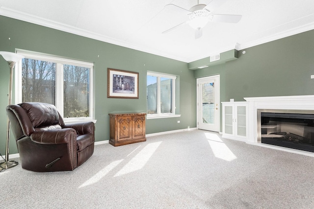 living area featuring baseboards, a fireplace, carpet flooring, and crown molding