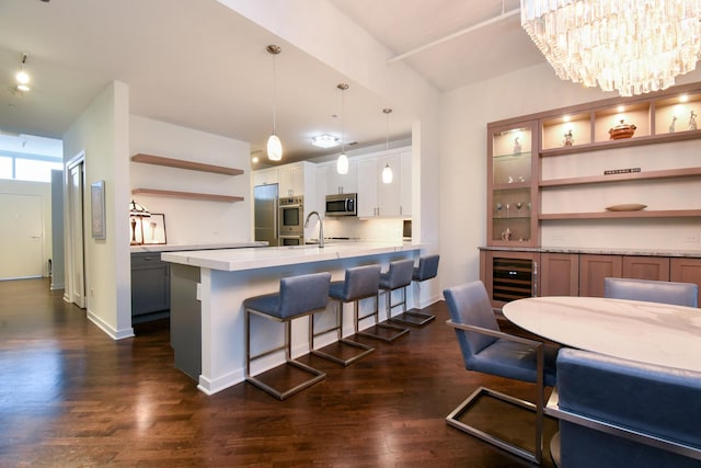 kitchen with white cabinetry, a breakfast bar, dark wood-type flooring, and pendant lighting